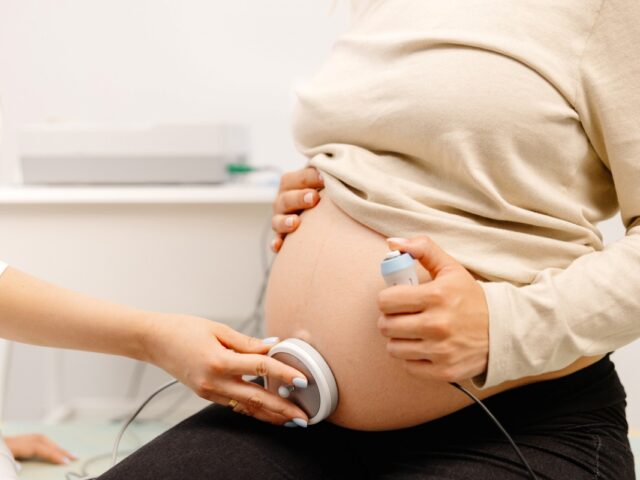 ciężarna kobieta na badaniu USG tarczycy w gabinecie lekarskim z lekarzem